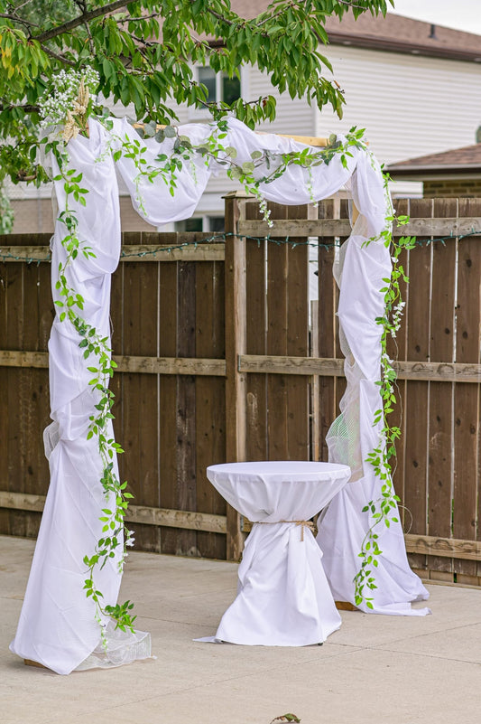 Decorative wedding arch with table set for ceremony with floral accents