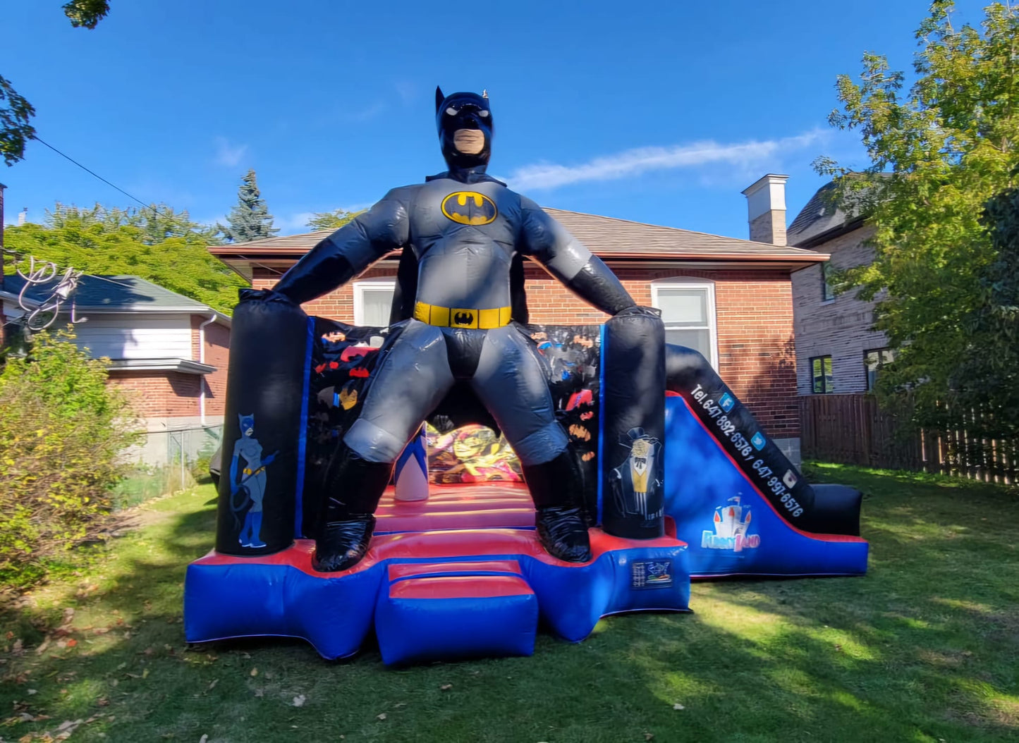 Batman bouncy castle with slide in blue and black, featuring superhero artwork for kids’ parties